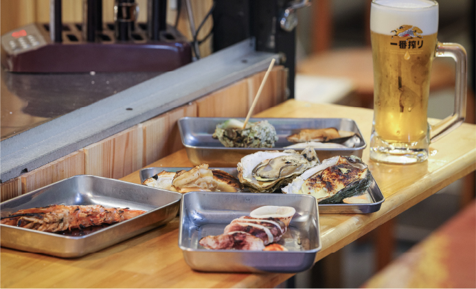 海鮮焼きやおでんが並ぶテーブルとキンキンに冷えた生ビール