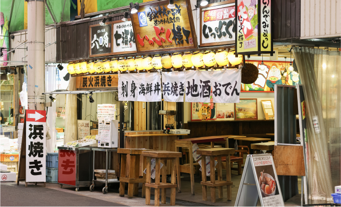 「炭火浜焼き」の看板が並ぶ、かち組カンパニーの活気ある店舗外観