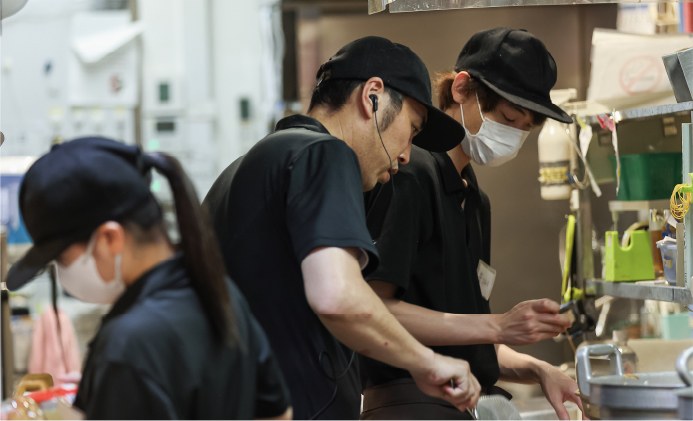 厨房で真剣に作業をする若手スタッフたちの連携風景